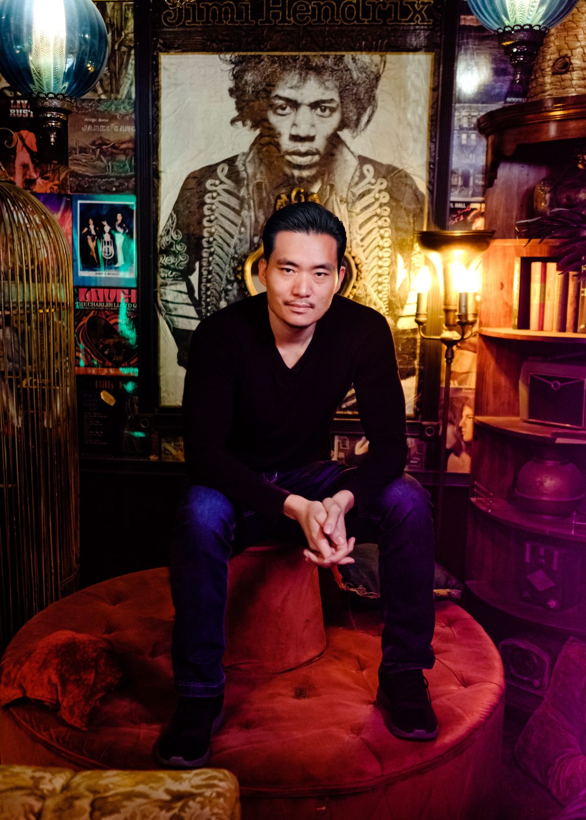 Young-H. Lee seated in front of a Jimi Hendrix portrait at FilmQuest