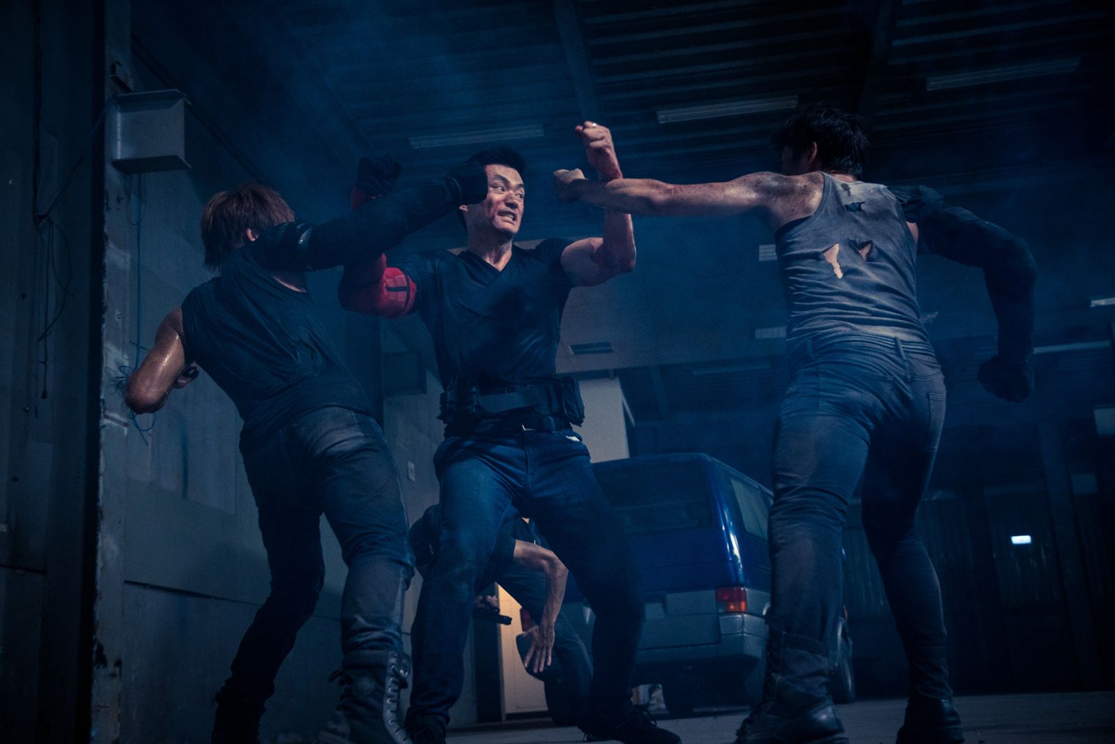 Kuang Feng fighting two attackers in a smoky warehouse