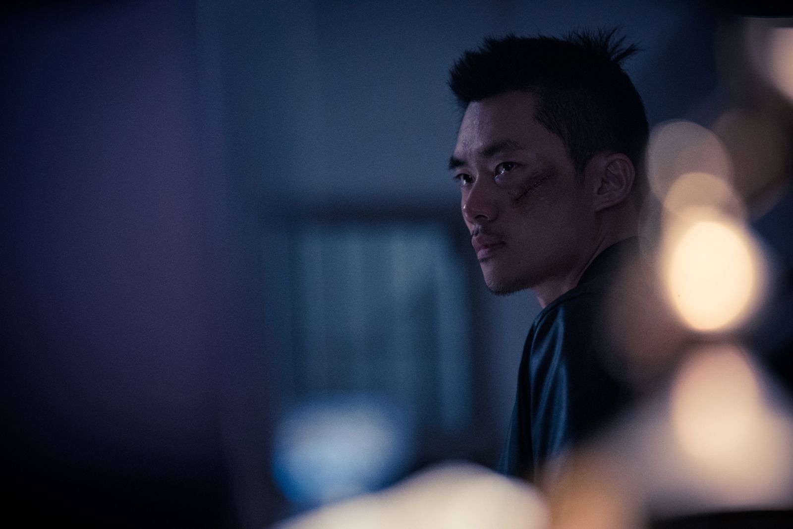 Kuang Feng in profile against blurred lights